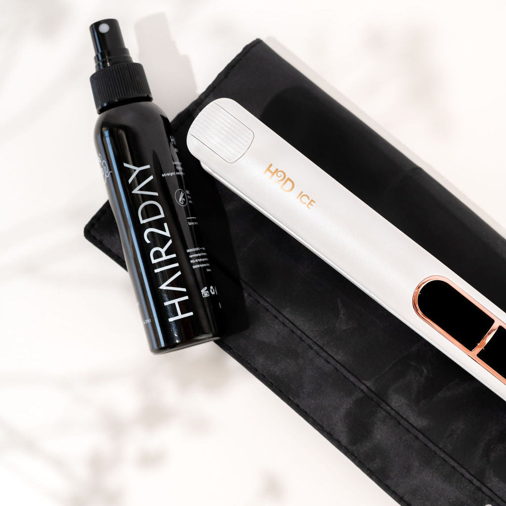 Hair2Day hair product bottle and white electronic device on a black pouch with a blurred background